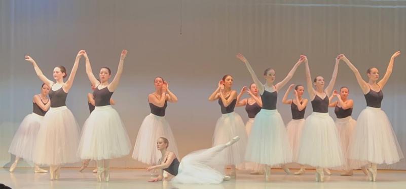 A group of dancers in black tops and white skirts.