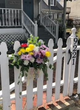 Flowers hanging on a white picket fence.